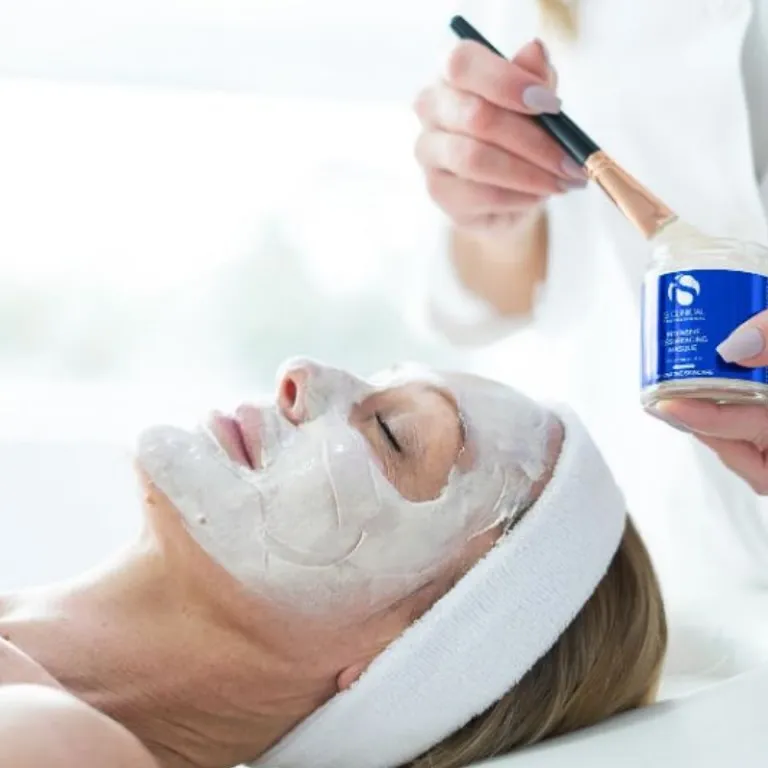 Hudterapeut applicerar ansiktsmask under en ansiktsbehandling på Salong Form Hud & Spa i Halmstad